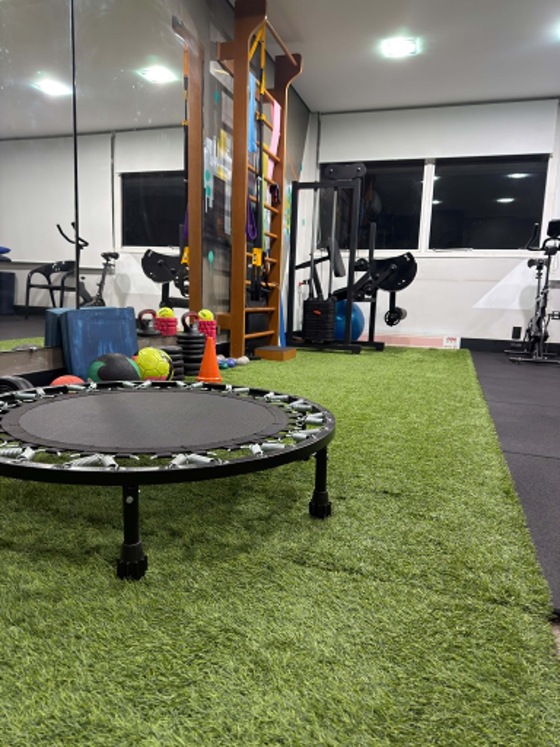 Área funcional com piso emborrachado tipo gramado sintético e equipamentos de treino