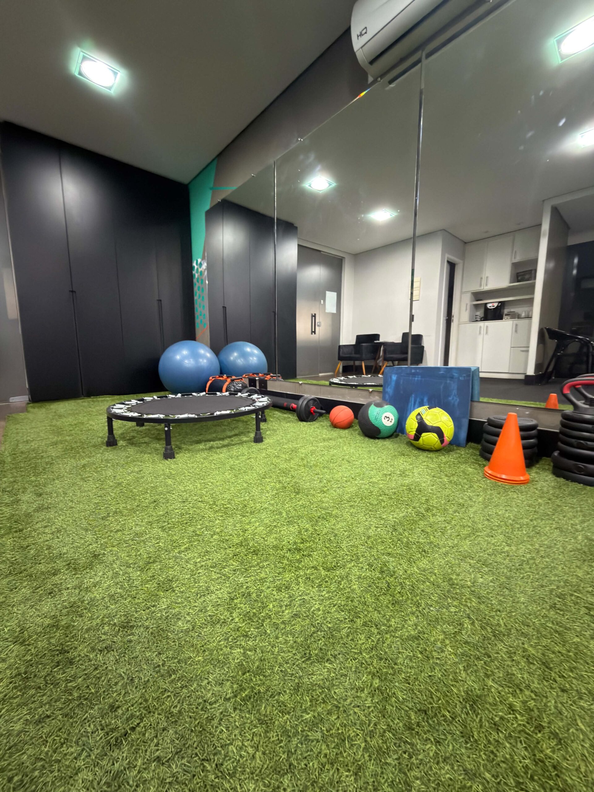 Espaço de treino funcional com piso tipo gramado e materiais de reabilitação